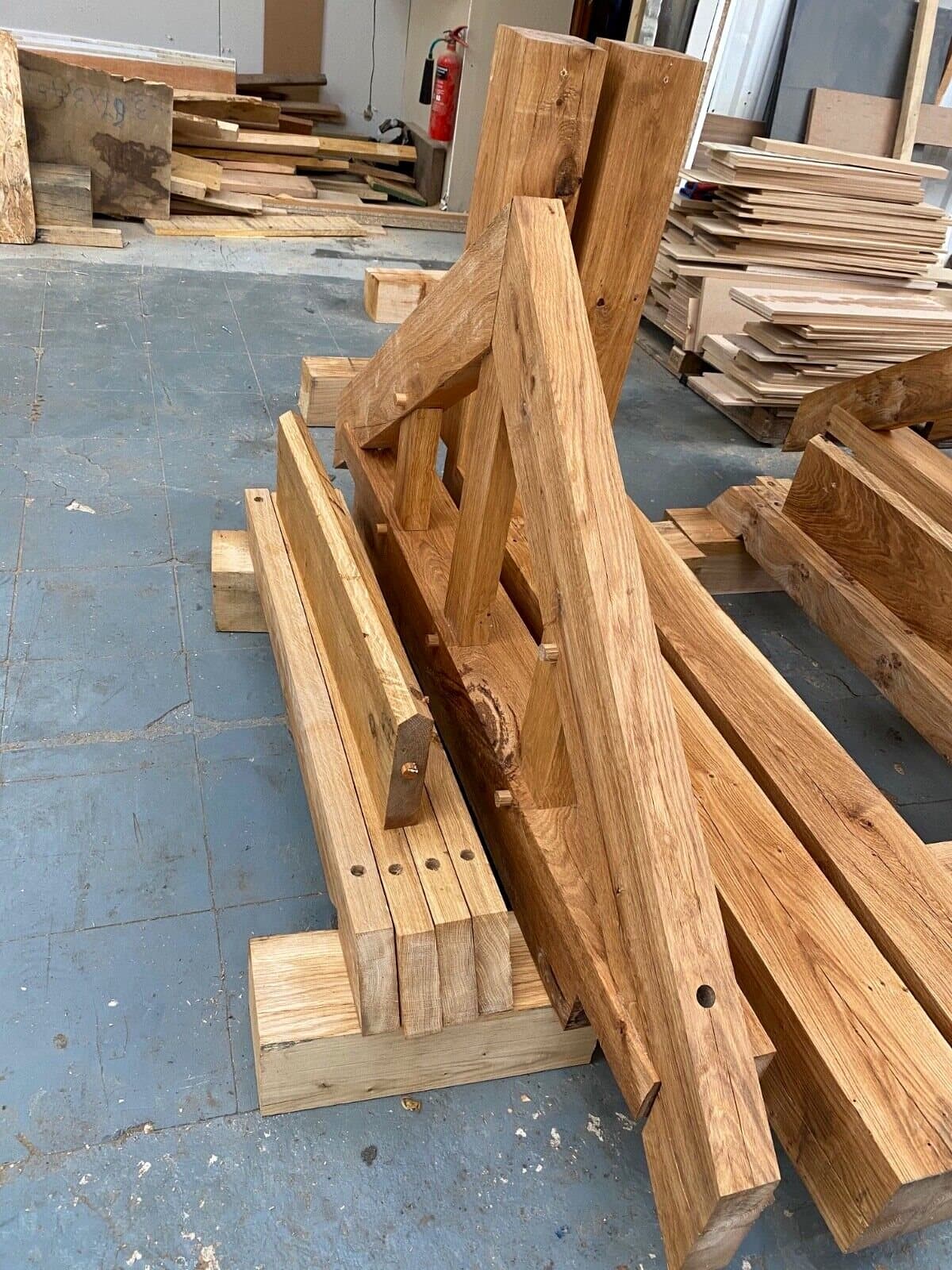 Pegged components of an oak porch kit stacked in the workshop before dispatch