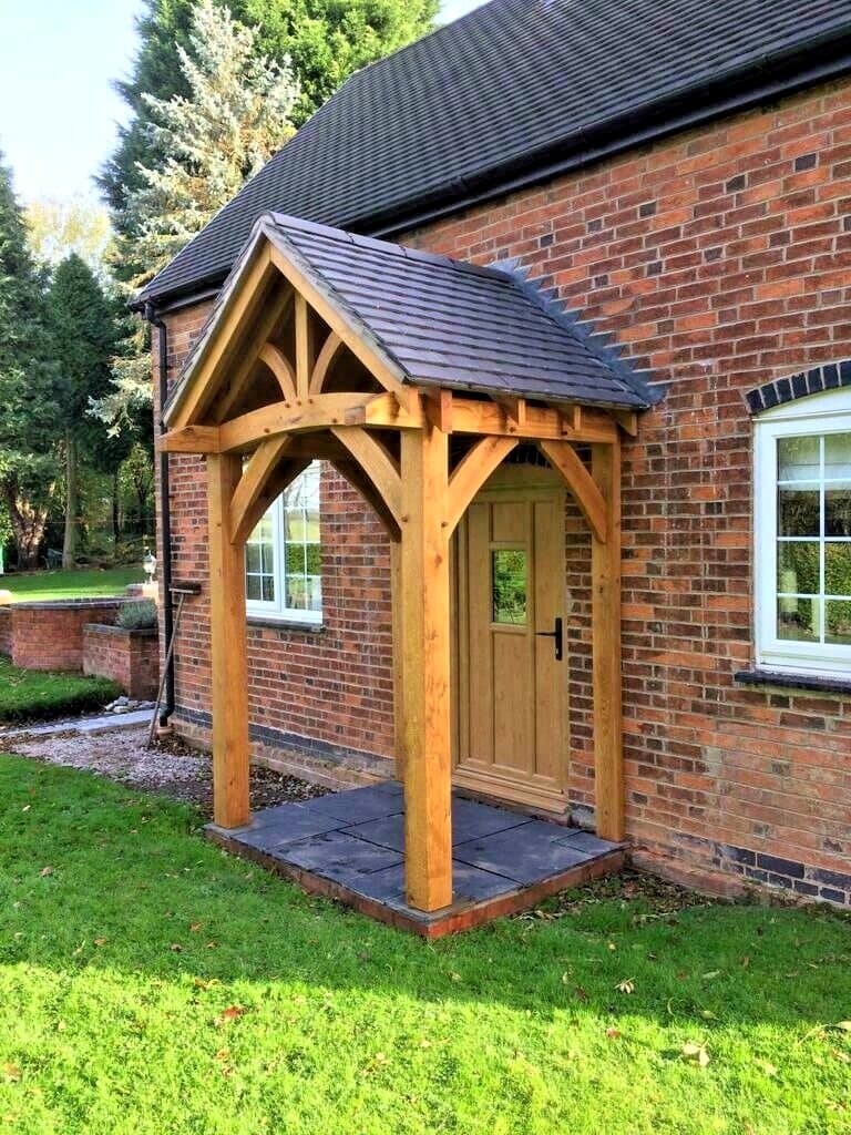 The Hereford oak porch on a red-brick home — full-height posts, curved beam and braces front and side, under a tiled gable roof