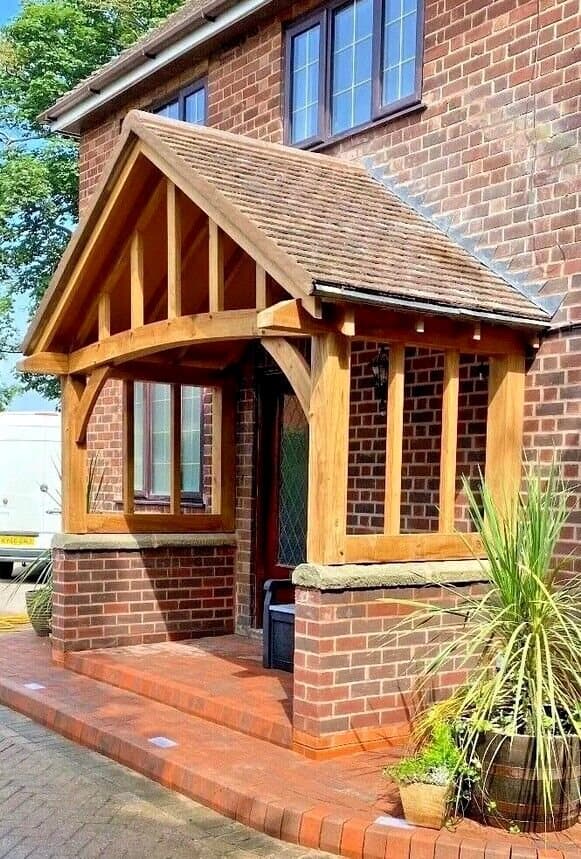 The Stroud oak porch on a brick home — grand curved beam over stone-capped dwarf walls, tiled to match the house
