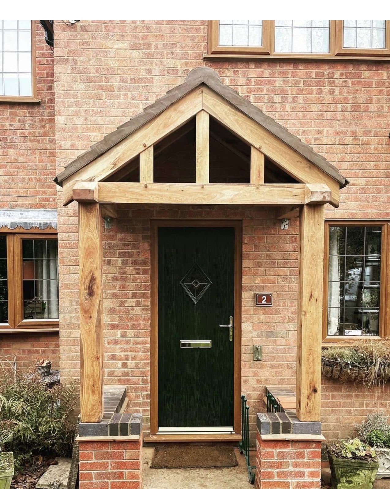 The Worcester oak porch on a red-brick house, posts on brick plinths framing a green front door